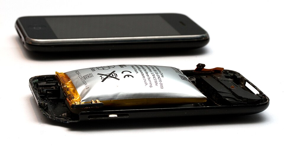 Disassembled iPhone 3GS with its swollen lithium polymer pouch battery lifting out of the opened case, an intact phone behind it